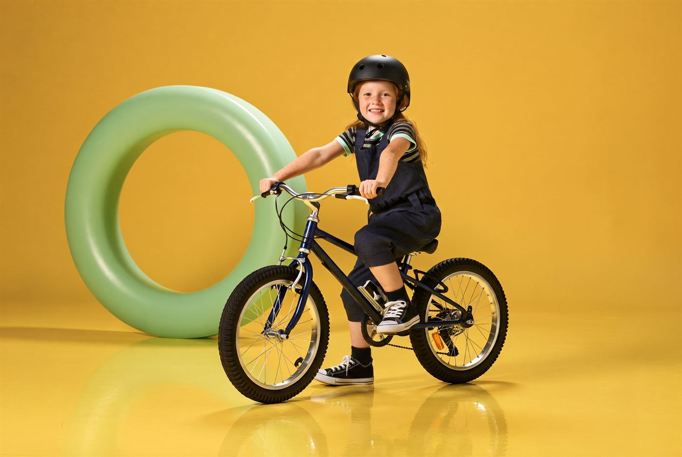 Kind van zeven fietst vrolijk over een fietspad langs bloemen