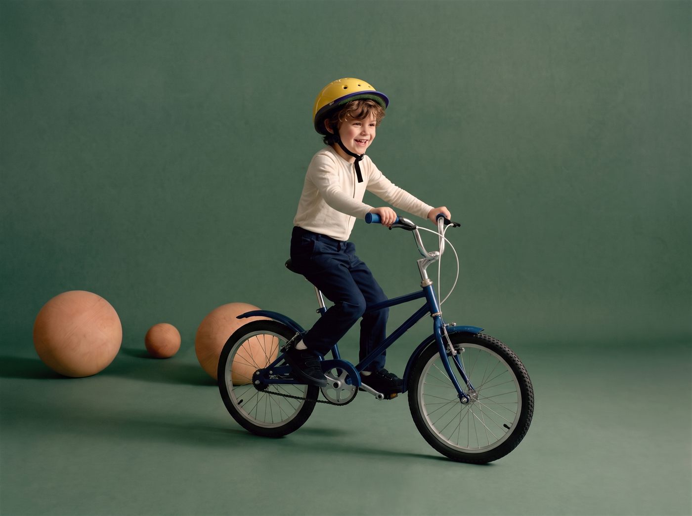 Jongen fietst vrolijk op zijn blauwe 16 inch kinderfiets in een zeegroene studioset