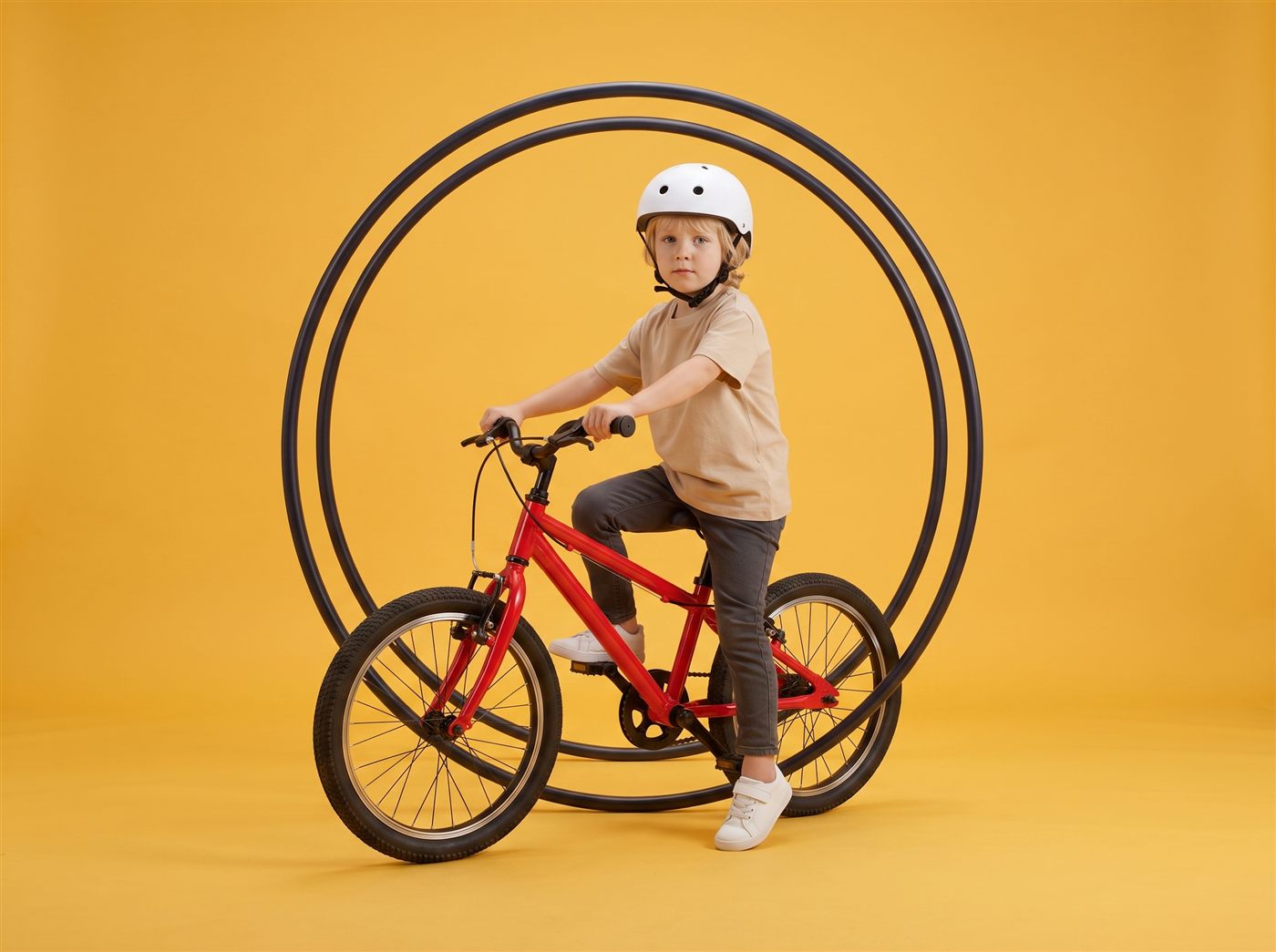 Jongen staat klaar om weg te fietsen op zijn rode 20 inch kinderfiets in een zonnig gele studioset