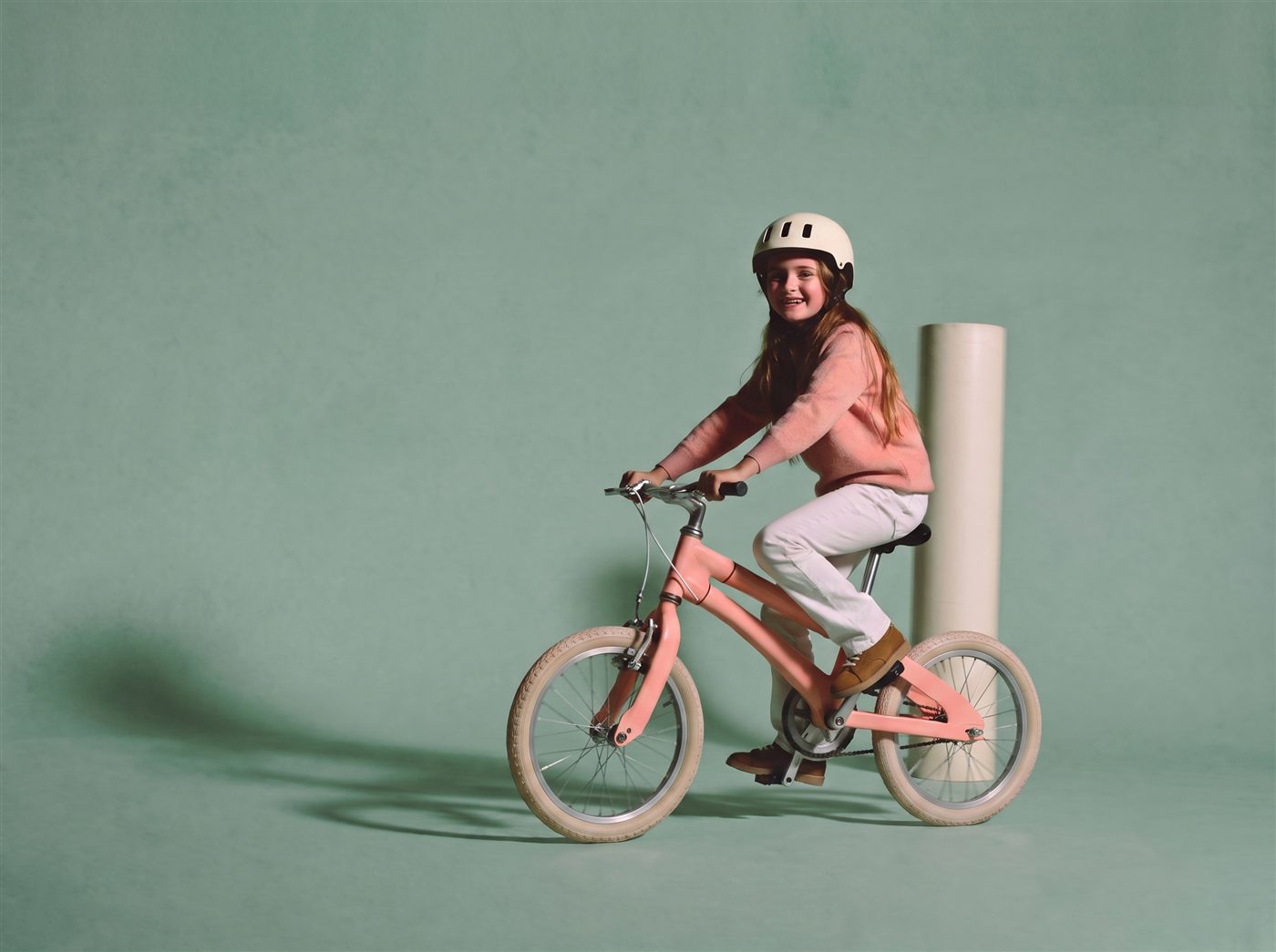 Meisje fietst ontspannen op haar roze 22 inch kinderfiets in een zachte teal studioset