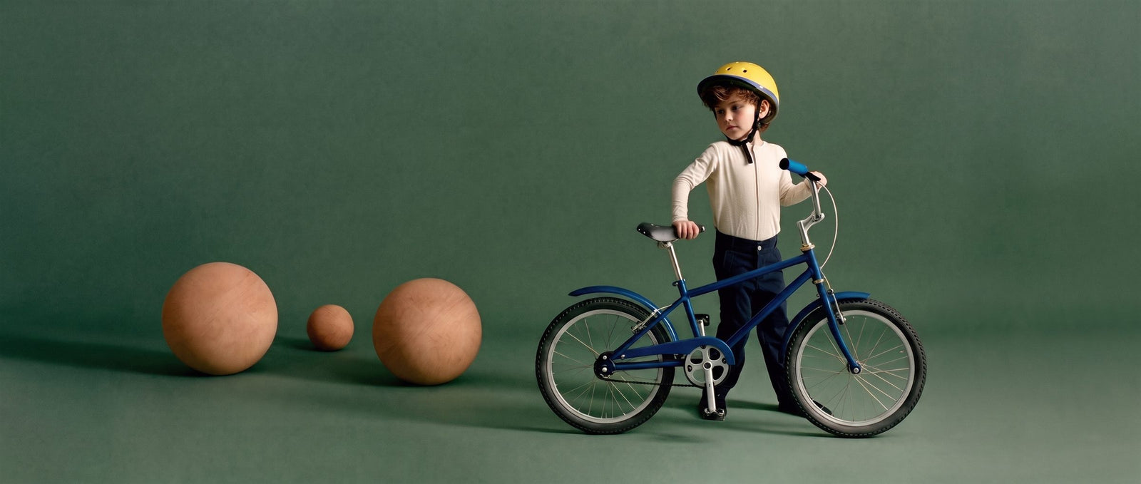 Jongen staat trots naast een blauwe 16 inch kinderfiets in een zeegroene studioset