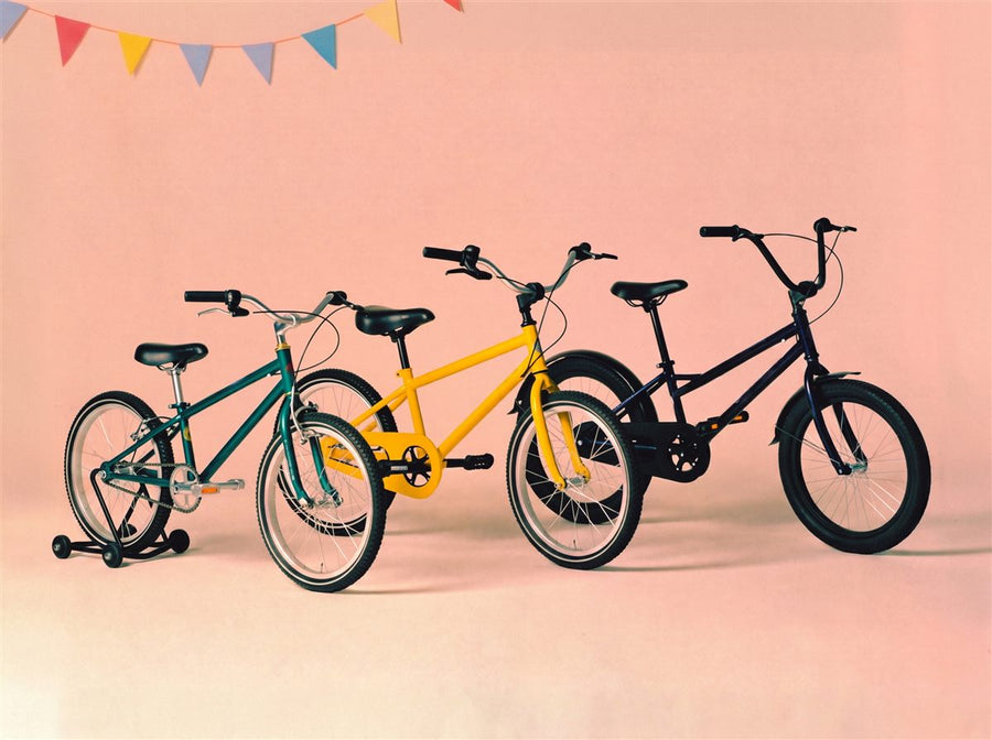 Drie kinderfietsen in zeegroen, geel en donkerblauw netjes op een rij