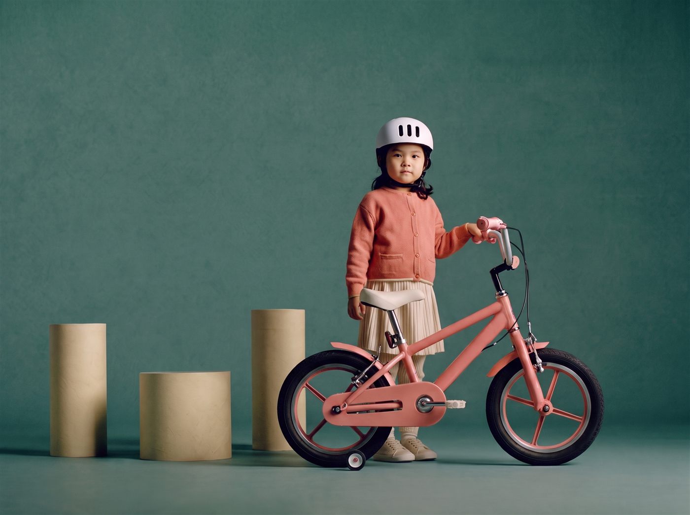 Meisje staat naast haar roze 14 inch kinderfiets in een zeegroene studioset